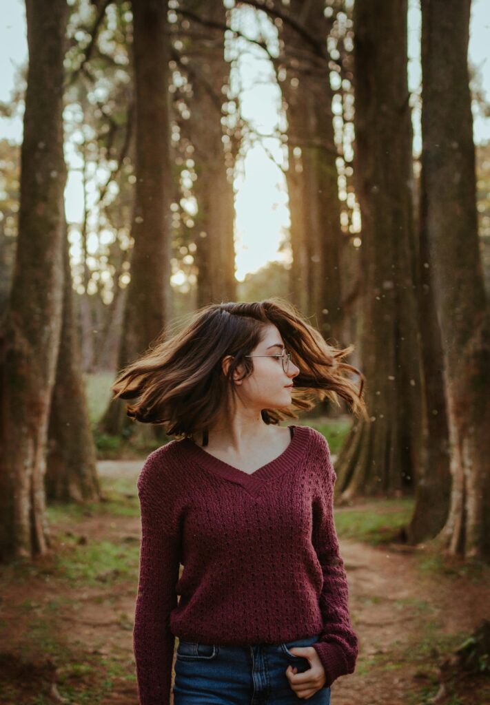 A young woman twirls in a forest, capturing the essence of nature and freedom.