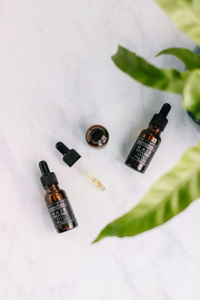 Flat lay of organic hair oil bottles with droppers on a marble surface.