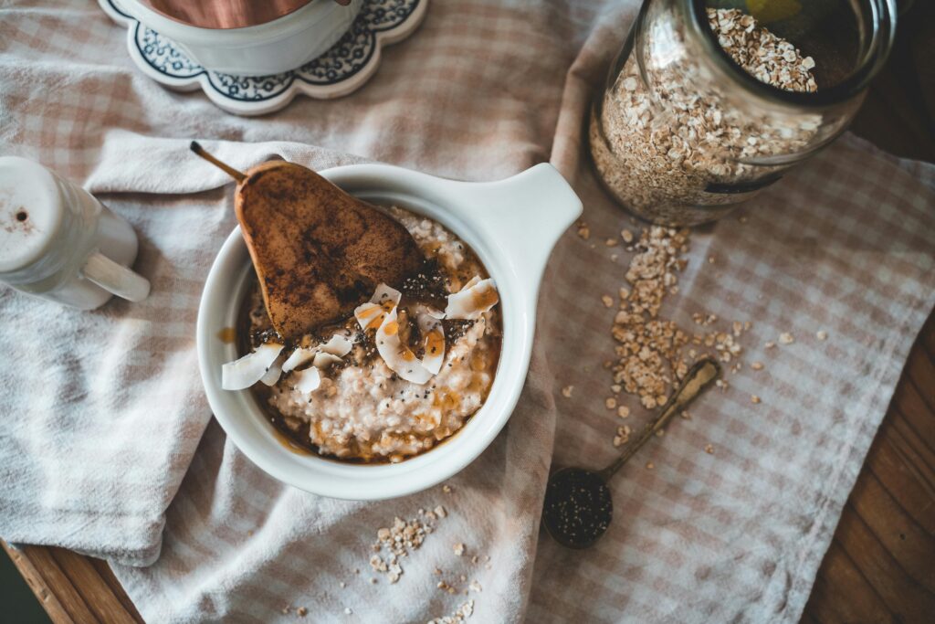 A cozy flatlay of oatmeal served with pear, coconut shavings, and honey.