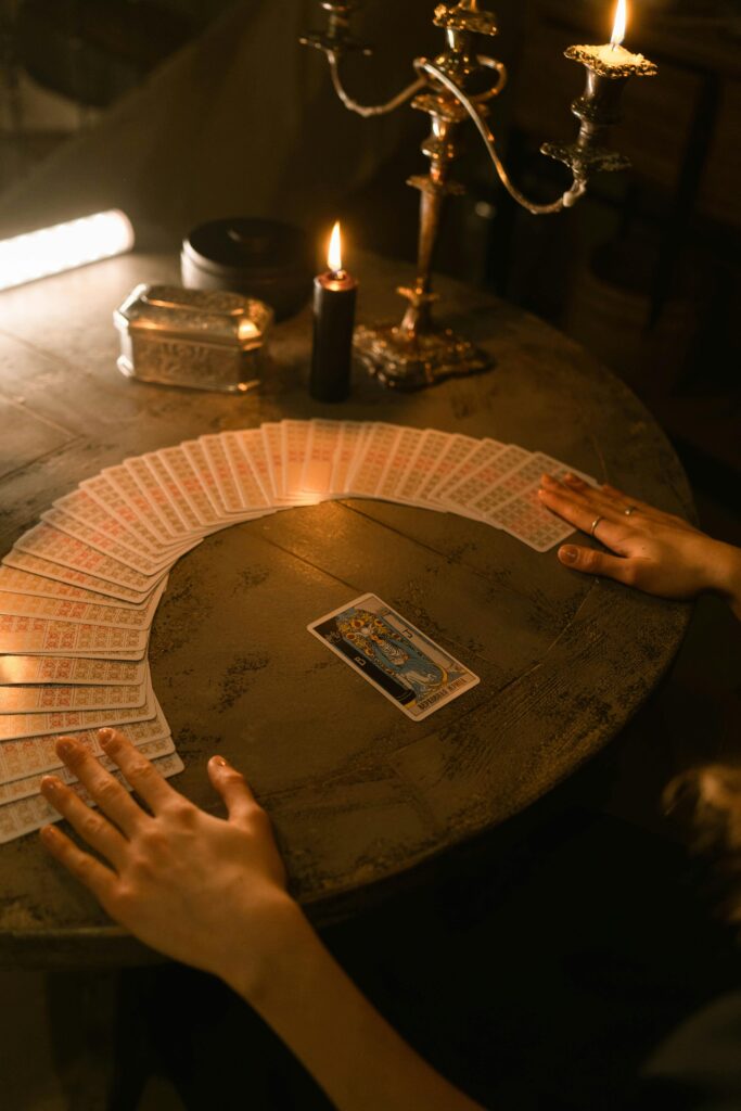 A mystical scene of tarot card reading with candles illuminating a wooden table.