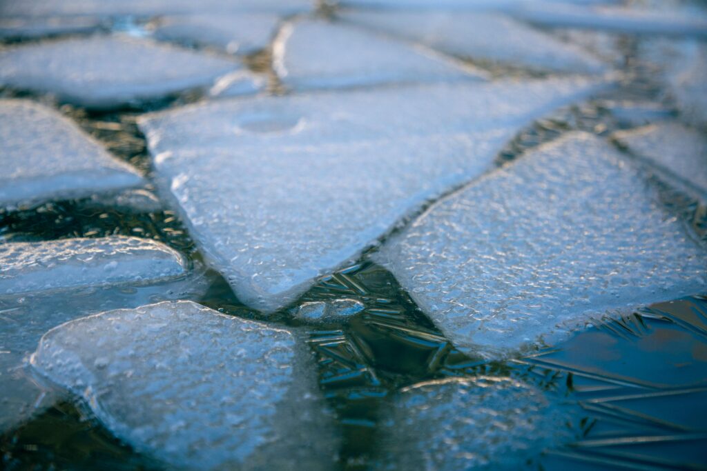 Detailed view of ice chunks floating on calm water, symbolizing winter and climate change.