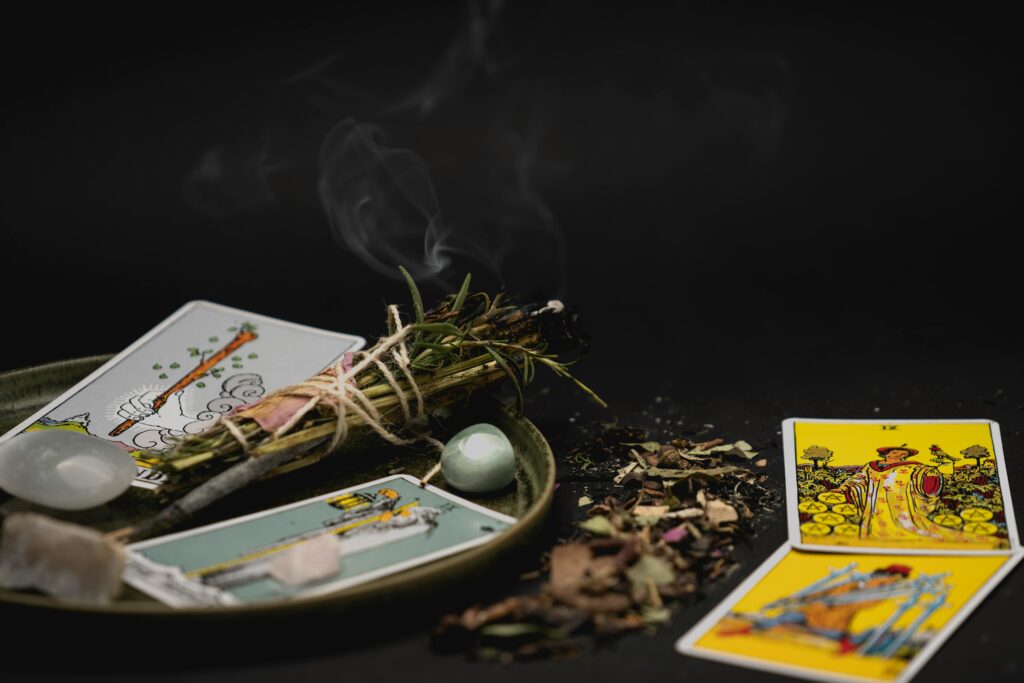 A spiritual still life with tarot cards, herbs, and crystals on a dark surface for meditation.