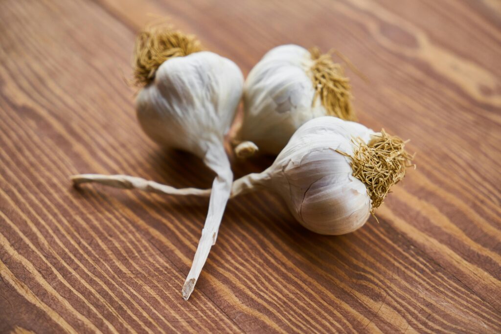 Close-up of fresh garlic bulbs on a wooden surface, highlighting natural texture and freshness.