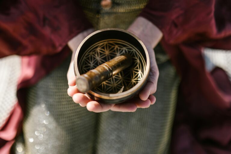 Close-up of hands holding a ornamental singing bowl, symbolizing spirituality and mindfulness.